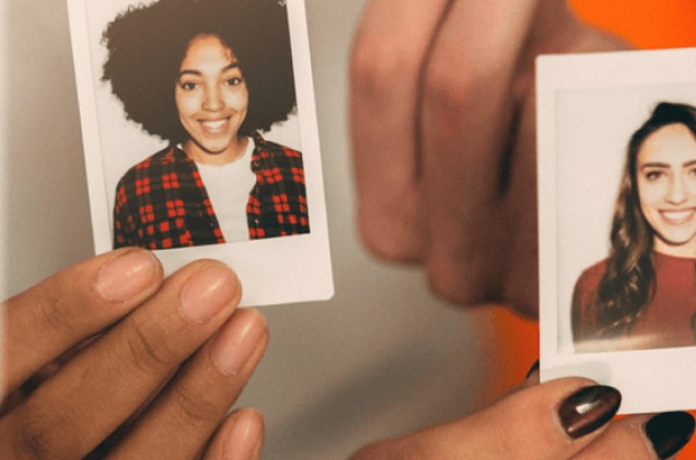 Hands holding two polaroid headshot photos of different women 